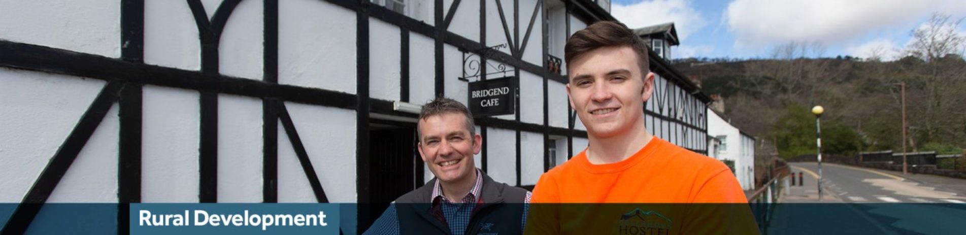 two-men-of-different-ages-smiling-outside-bridgend-cafe-in-callander-text-reads-rural-development