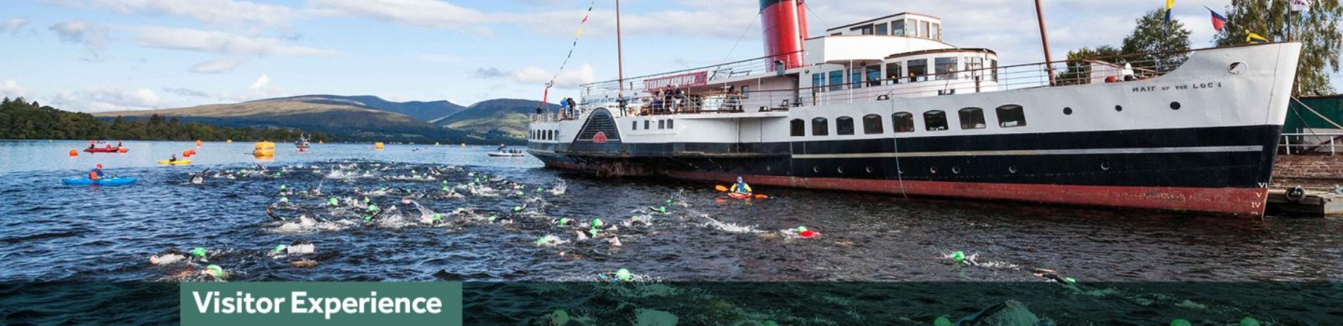 great-scottish-swim-event-on-loch-long-dozens-of-swimmers-wearing-colourful-caps-swim-in-water-next-to-maid-of-the-loch-steamship