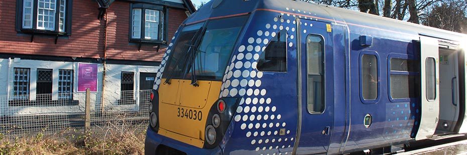 scotrail-train-stationed-in-balloch-station-with-tullie-inn-building-white-and-orange-behind