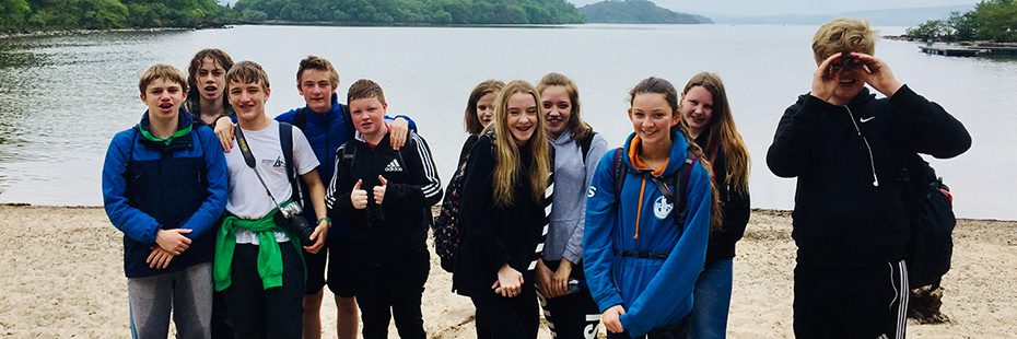 balfron-high-school-pupils-boys-and-girls-on-inchcailloch-beach-with-lush-loch-lomond-islands-behind-and-loch-waters-cloudy-day