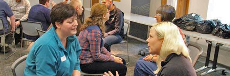 emma-white-volunteer-ranger-talking-to-national-park-staff-with-larger-group-behind-in-national-park-headquarters-room