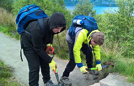 Two young volunteers clearing a hill path