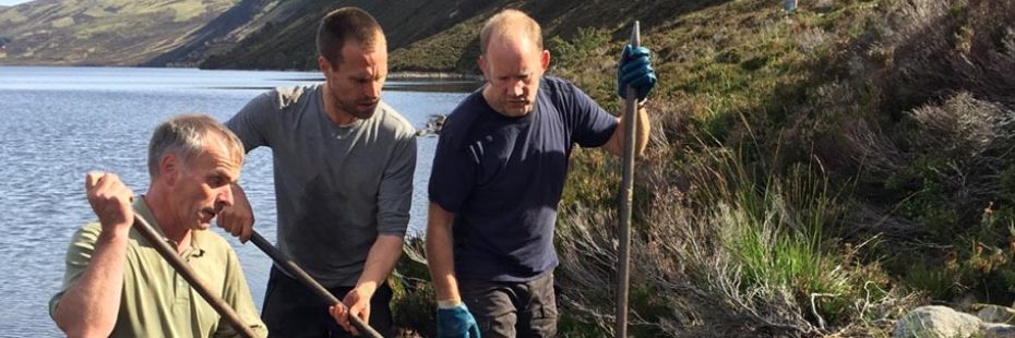 three-national-park-male-volunteers-holding-spades-engaged-in-path-restoration-at-the-edge-of-loch