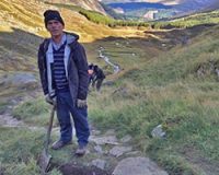 euan-ramage-national-park-volunteer-holding-spade-on-mountain-track-restoration-with-lush-landscape-behind