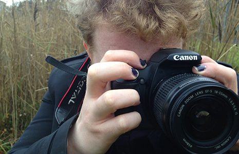 close-up-of-young-man-holding-dslr-camera-and-taking-a-snapshot