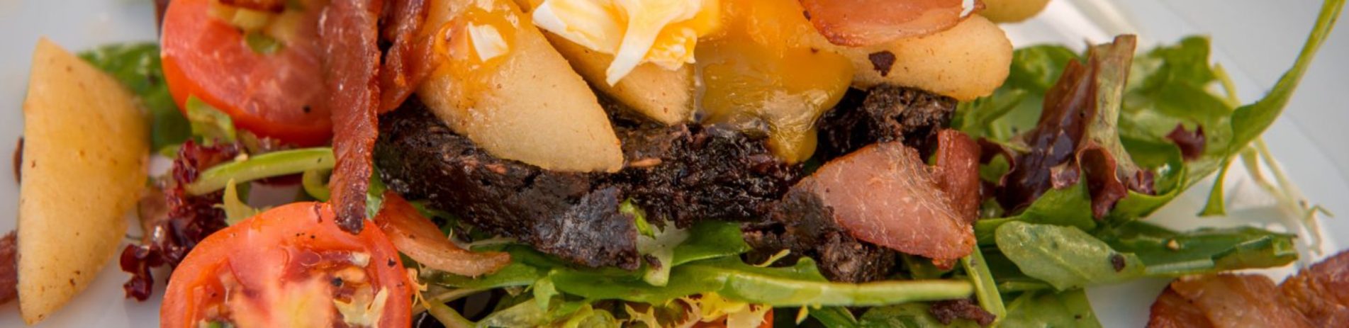 black-pudding-with-fresh-vegetables-salad-and-topped-with-omelette-on-white-plate