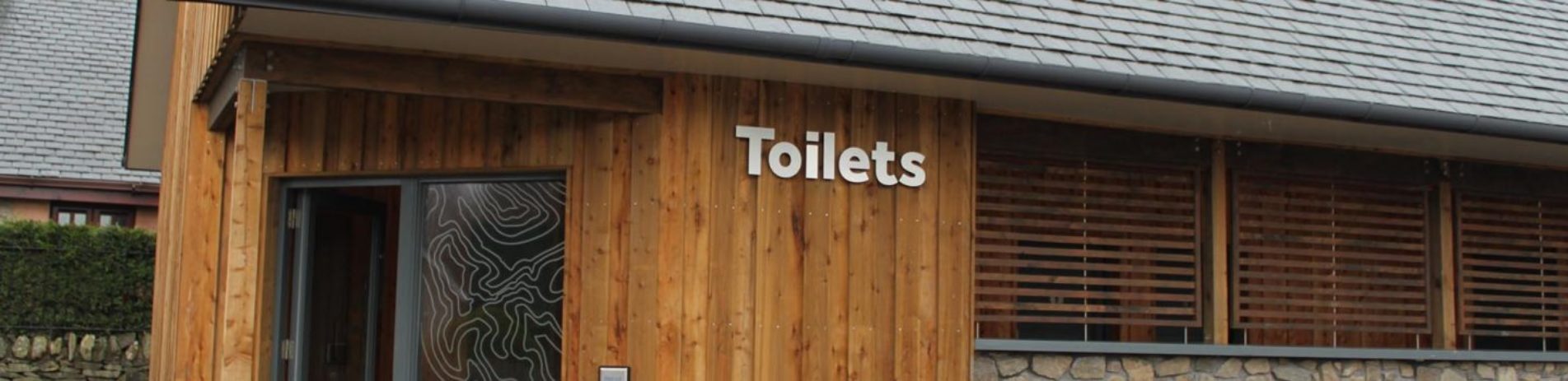 toilet-block-at-luss-village-wooden-exterior-with-sleet-roof-and-stylized-hill-contours-graphic-on-glass-doors