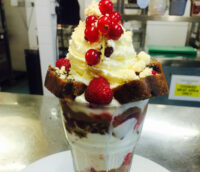 sundae-with-cream-and-cranberries-in-tall-glass-on-table