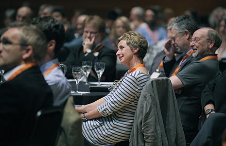 conference-close-up-of-audience-smiling-and-watching-interested-on-the-left-of-the-picture-they-are-wearing-orange-lanyards