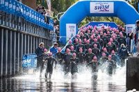 great-scottish-swim-swimming-event-swimmers-in-black-wetsuits-and-pink-caps-running-in-loch-lomond-at-race-start-with-large-gate-like-inflatable-marking-start