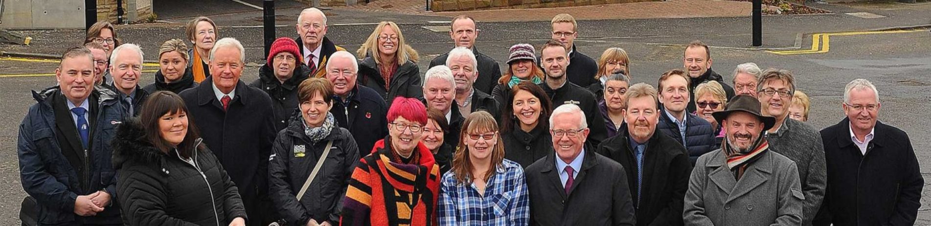 large-group-of-callander-locals-gathered-for-the-inauguration-of-new-affordable-homes-roughly-half-are-men-and-half-are-women-all-dressed-in-jackets-and-coats-and-smiling