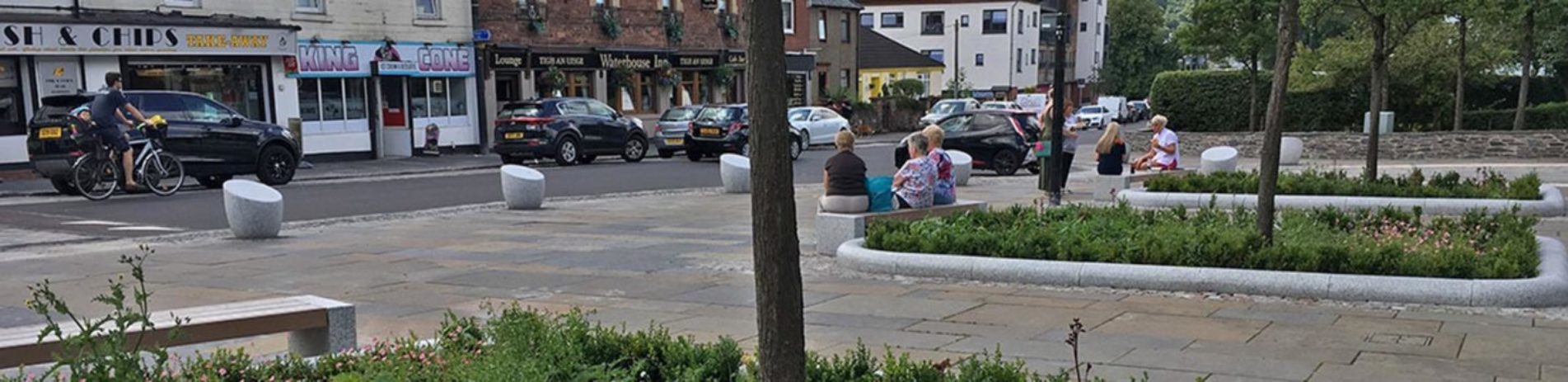 new-balloch-square-after-refurbishment-with-people-sitting-on-benches-cars-parked-and-a-cyclist-on-road