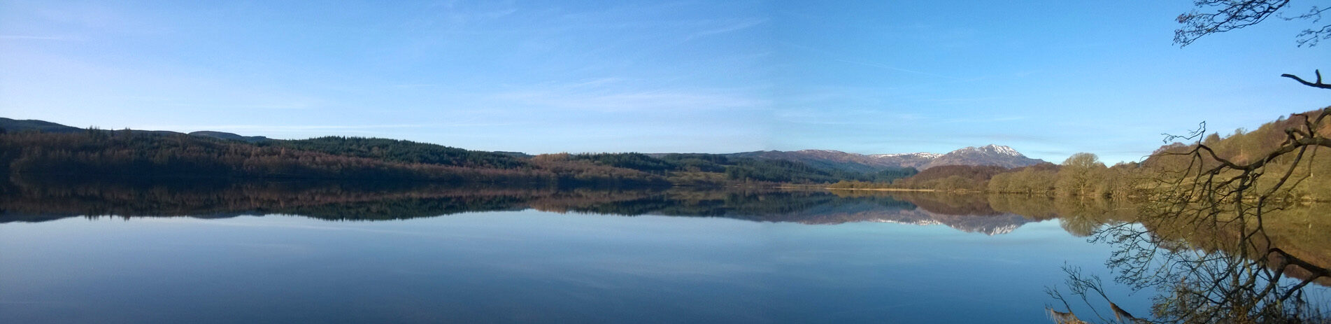 loch-venachar-in-autumn-surrounded-by-forests-in-the-distance