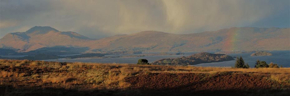 loch-lomond-with-islands-and-ben-lomond-visible-in-the-distance-as-well-as-rainbow-over-water-on-the-right