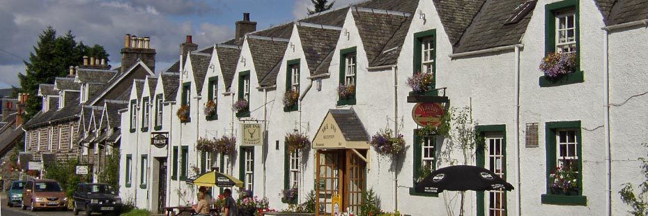 row-of-white-washed-stone-buildings-with-flowers-outside-in-strathyre-village