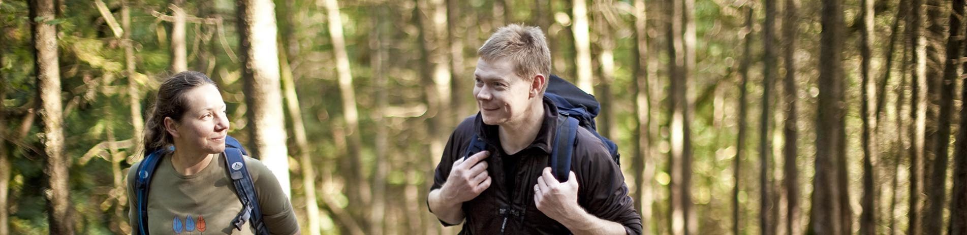 woman-and-man-walking-couple-with-small-backpacks-in-the-forest