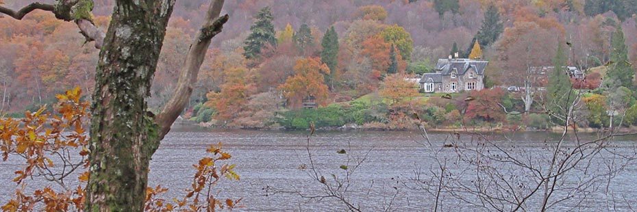 loch-ard-surrounded-by-woods-and-houses-draped-in-autumn-colours