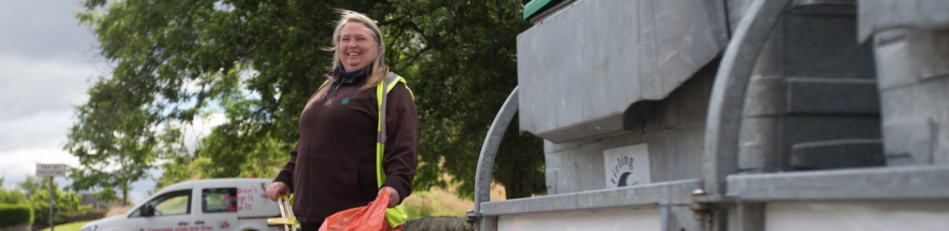 Stirling-Council-staff-member-holding-litter-picker-and-bin-bag-next-to-bin