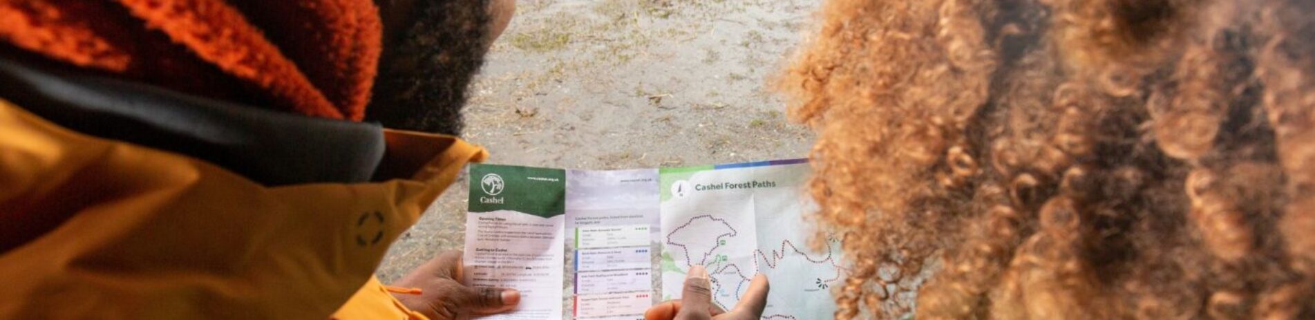 looking over a persons shoulder who is looking and pointing at a map.