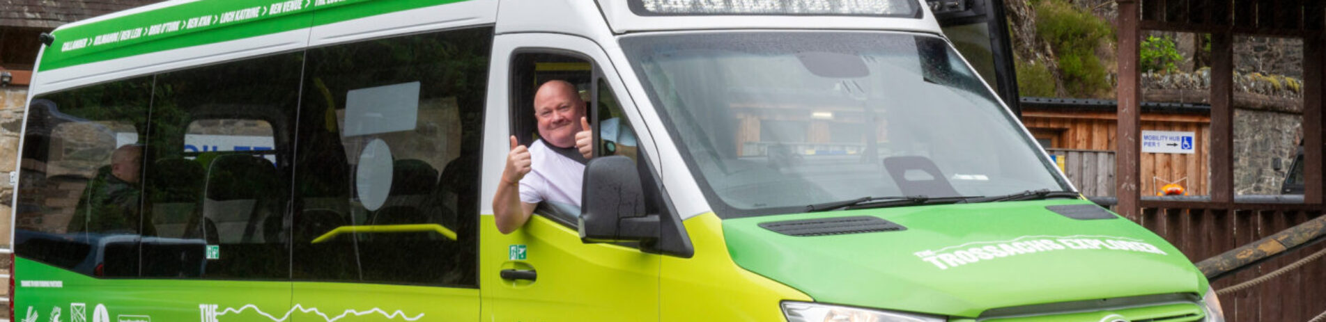 Side view of Trossachs Explorer bus with cheery driver